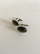 タイガーアイをあしらったシルバーのオーバルカフリンクス。